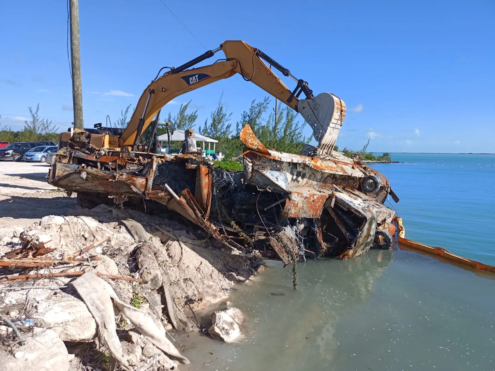 Excavator salvaging a wrecked boat from the shoreline